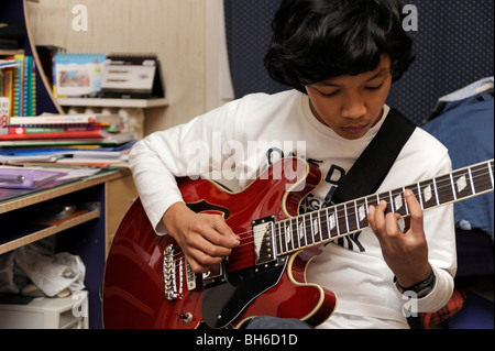 Garçon jouer avec une guitare jazz Aria, style Gibson 335 Banque D'Images