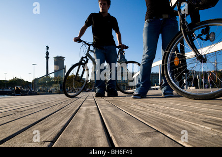 Cycliste de Rambla del Mar à la passerelle et le Maremagnum statue de Christophe Colomb à l'arrière ,Barcelone. Banque D'Images