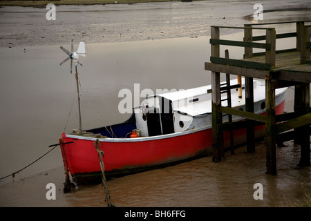 Bateau avec coque rouge amarré dans la boue sur River Deben, Melton, Suffolk, Angleterre Banque D'Images