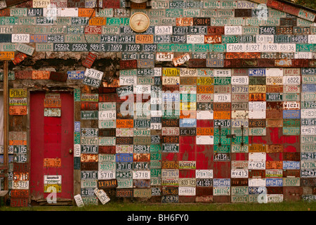 Mur de plaques d'immatriculation voiture métal sur garage avec porte rouge Banque D'Images