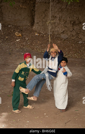 Trois garçons jouant sur une corde swing dans l'Egypte rurale Banque D'Images