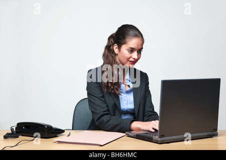 Young businesswoman assis à un bureau de la saisie sur un ordinateur portable Banque D'Images