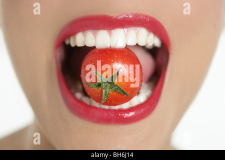 Manger une tomate rouge femme de macro dents et bouche lèvres rouge Banque D'Images