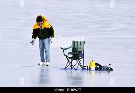 Homme seul la pêche blanche sur lac gelé avec chaise et engins à Cape Cod USA Banque D'Images