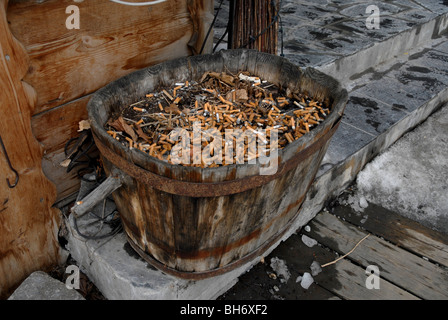 L'article de vieux tonneau en bois assis sur l'étape à l'entrée du restaurant plein de mégots de cigarettes Banque D'Images