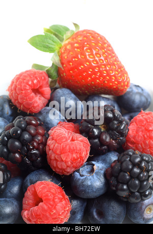 Une pile de baies, bleuets, framboises, mûres et une fraise, sur un fond blanc. Banque D'Images