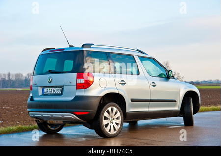 Vue latérale, arrière Skoda Yeti SUV, 2010 modèle à la lumière bleu métallisé stationné sur une rue à côté d'un champ Banque D'Images