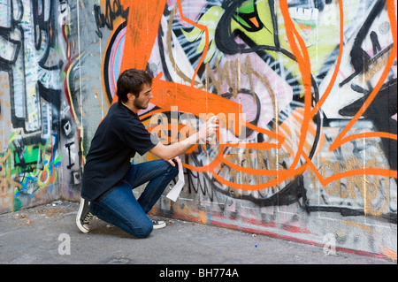 La peinture par pulvérisation des graffiti sur mur de béton, South Bank, Londres, Angleterre, Royaume-Uni. Banque D'Images