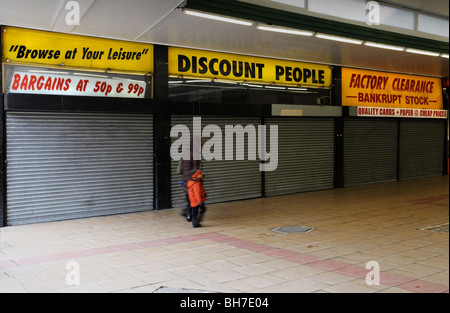 Femme et enfant en passant devant la boutique d'escompte fermée, Croydon, Londres, Angleterre, Royaume-Uni. Banque D'Images