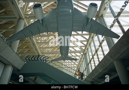 Une maquette d'un avion de ligne Airbus est suspendu au-dessus d'un passager au départ qui monte un escalator à l'aéroport de Francfort. Banque D'Images