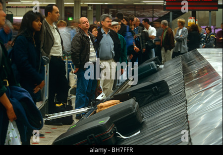Des foules d'arrivée pour attendre leurs bagages pour arriver sur un carrousel pendant une longue fin de semaine de congé à l'aéroport de Glasgow. Banque D'Images