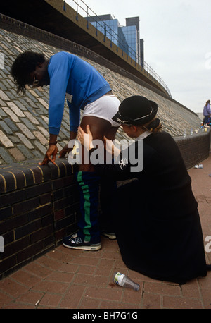 Marathon de Londres une crampe de l'athlète est aidé par une jeune fille St John's Ambulance medic. Banque D'Images