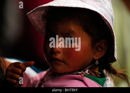 L'Équateur, Otavalo, close-up portrait d'une fille d'âge préscolaire à la recherche sur l'épaule avec un chapeau blanc et les pommettes brûlées par le Banque D'Images
