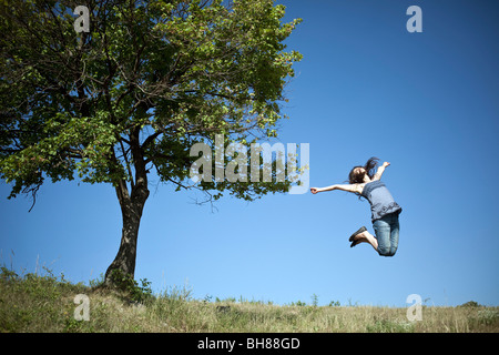 Femme sautant par tree Banque D'Images