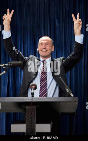 Un homme en costume debout à un pupitre et gesturing Banque D'Images