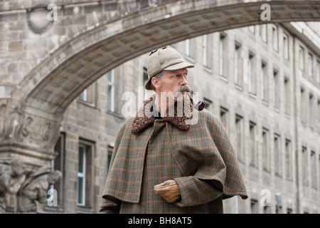 Un homme habillé comme Sherlock Holmes debout sous un bâtiment arch looking away Banque D'Images