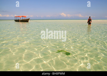 Tourisme patauge dans un crachat en jaunes d'eau de mer à marée basse au large plage de Nungwi, le paradis tropical à zanzibar Banque D'Images