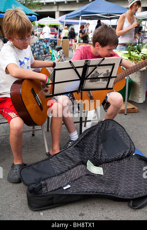 L'exécution de deux jeunes garçons, joueurs de guitare, la concentration difficile et la lecture musicale à partir de feuilles sur un support musical Banque D'Images