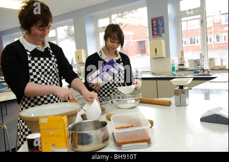 Deux adolescents, garçons et filles, élèves - décrire les ingrédients en science alimentaire Cours de cuisine , secondary school UK Banque D'Images