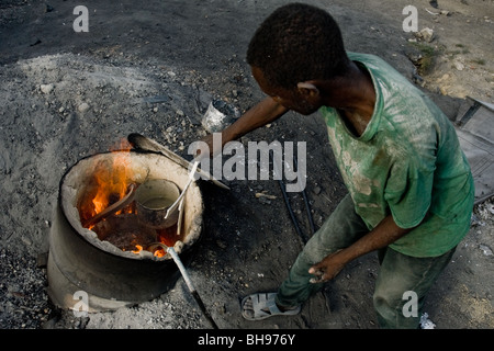 Un Haïtien fonctionne avec de l'aluminium fondu pour faire un pot de cuisine dans l'atelier de recyclage de l'aluminium à Port-au-Prince, Haïti. Banque D'Images