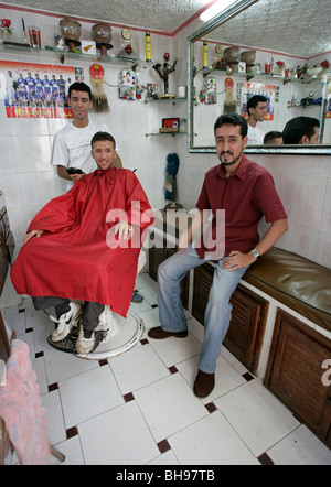 C'est un petit salon de coiffure où un homme obtient une coupe alors que l'autre attend son tour. Banque D'Images