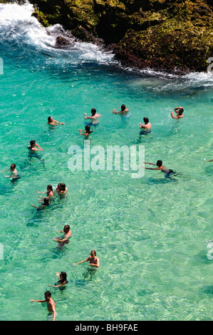 Nageurs à point Lookout North Stradbroke Island Australie | NORTH STRADBROKE ISLAND, Australie — les nageurs se rassemblent dans une crique dégagée et abritée de rochers à côté du promontoire à point Lookout, l'un des rares endroits où le substrat rocheux plutôt que le sable rencontre la mer sur Minjerribah. L'occupation de l'île par Quandamooka est datée d'au moins 21 800 ans et, en 2024, date de luminescence, peut-être aussi loin que 30 000 à 49 000 ans, parmi les plus anciennes mentions sur la côte est de l'Australie. Banque D'Images