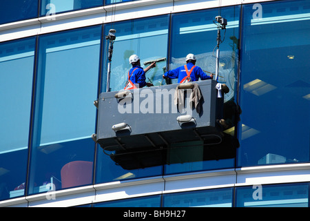 Nettoyage de vitres dans un berceau suspendu lave-verre murs-rideaux d'un grand immeuble de bureaux avec une façade en verre, Londres Banque D'Images