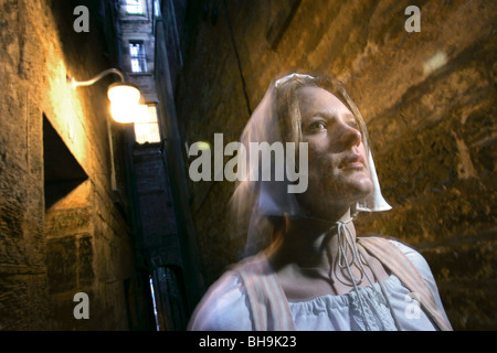 Guide d'une femme vêtue comme une 16e siècle personnage apparaît dans une ruelle fantomatique d'Édimbourg Banque D'Images