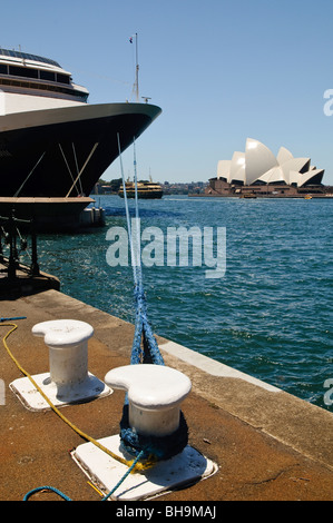 Sydney Opera House Cruise Ship Circular Quay Sydney Australie // SYDNEY, Australie — Un grand bateau de croisière est amarré à Circular Quay, à côté du quartier des Rocks, avec l'Opéra de Sydney en arrière-plan. Des lignes d'amarrage sécurisent le navire au quai, tandis qu'un ferry navigue dans les eaux scintillantes du port de Sydney. Banque D'Images
