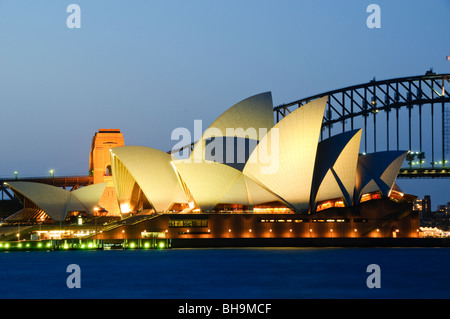 Opéra de Sydney Sydney Harbour Bridge Sydney Australie // SYDNEY, Australie — L'emblématique Opéra de Sydney est illuminé la nuit avec le Sydney Harbour Bridge visible en arrière-plan, vu depuis MRS Macquarie's point. Le site des arts de la scène classé au patrimoine mondial de l'UNESCO, conçu par l'architecte danois Jørn Utzon et achevé en 1973, présente ses coquilles en forme de voile caractéristiques qui sont devenues synonymes de la plus grande ville d'Australie. MRS Macquarie's point, situé dans les jardins botaniques royaux, offre l'un des points de vue les plus populaires pour photographier le monde de Sydney Banque D'Images