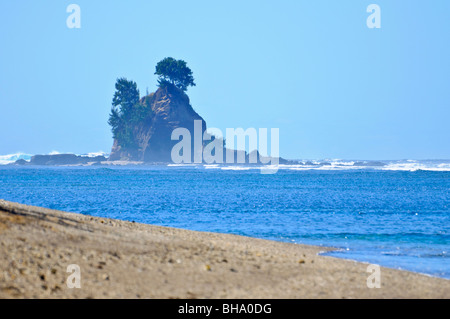 Rock formation au large depuis une plage tropicale non découvertes, avec les vagues de l'océan Banque D'Images