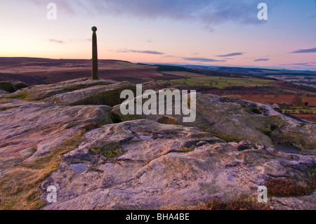 Les hivers d'un lever de soleil sur le bord noir-argenté dans le parc national de Peak District, avec Nelsons Monument debout fier sur le bord rocheux. Banque D'Images