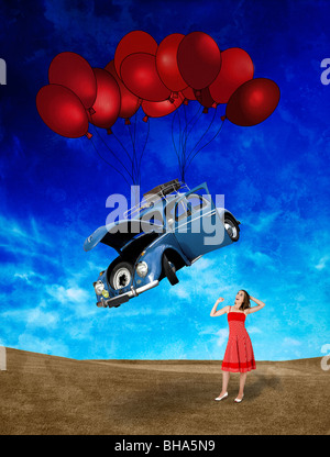 Witing femme pour une voiture beetle tombant du ciel avec des ballons Banque D'Images