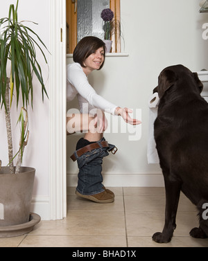 Tourné d'une femme 30s dans la salle de bains et de chien ce qui porte le rouleau de papier toilette Banque D'Images