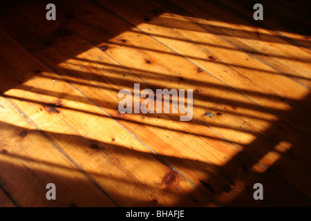 La lumière du soleil tombant sur le plancher ciré en bois, la création d'ombre. Banque D'Images