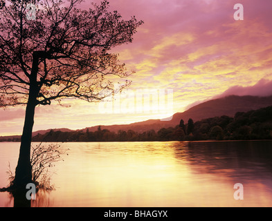 Ciel rouge le coucher du soleil sur l'eau et de Coniston en silhouette des arbres dans le Parc National de Lake District. Coniston, Cumbria, England, UK, Grande-Bretagne Banque D'Images