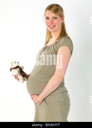 Pregnant woman holding child's teddy bear Banque D'Images