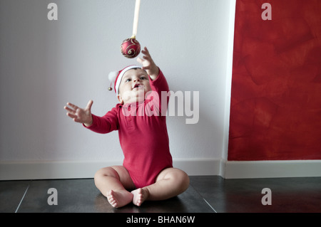 Baby Boy sitting on floor vers de boule de Noël Banque D'Images