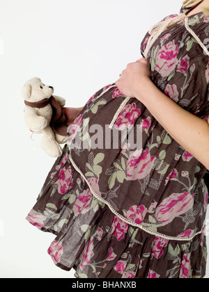 Pregnant woman holding child's teddy bear Banque D'Images