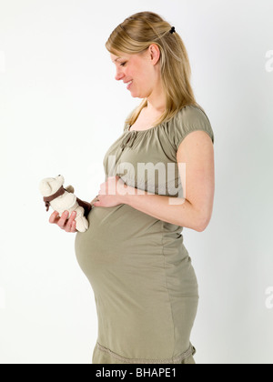 Pregnant woman holding child's teddy bear Banque D'Images