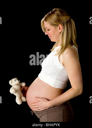 Pregnant woman holding child's teddy bear Banque D'Images