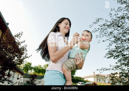 Jeune femme dansant dans jardin avec baby boy Banque D'Images