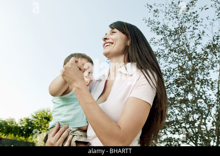 Jeune femme dansant dans jardin avec baby boy Banque D'Images