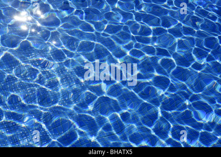 La texture de l'eau bleu, carreaux piscine en journée ensoleillée avec des reflets de lumière Banque D'Images