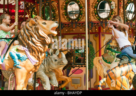 Young woman taking photo de petite fille alors qu'carousel au zoo Audubon. Banque D'Images