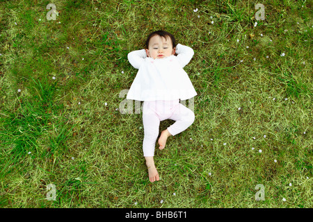 Le Japon, Préfecture de Saitama, baby girl lying on grass Banque D'Images