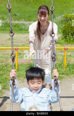 Le Japon, Tokyo Prefecture, mère poussant son on swing Banque D'Images