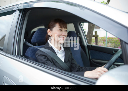 Le Japon, Tokyo Prefecture, Businesswoman driving car, smiling Banque D'Images