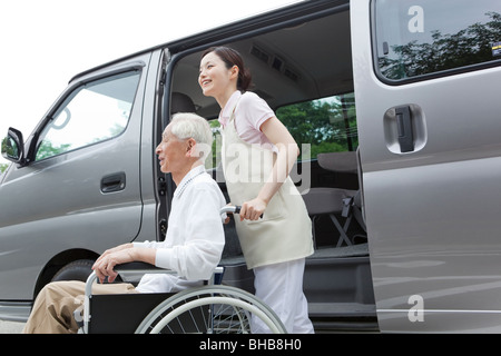 Le Japon, Tokyo Prefecture, infirmière avec man sur fauteuil roulant, side view Banque D'Images