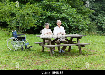 Le Japon, Tokyo Prefecture, Senior couple in park, man and woman knitting, smiling Banque D'Images